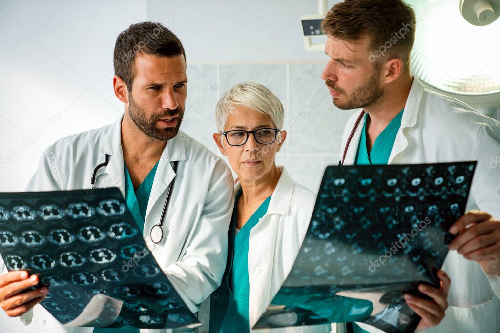 Group of doctors discussing patient's diagnosis looking at x-rays in a hospital