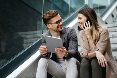 Başarılı genç iş adamları, tasarımcılar konuşuyor, modern iş binası önünde birlikte çalışıyorlar.