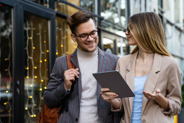 Portrait of two successful smiling business people walking and talking together in urban background