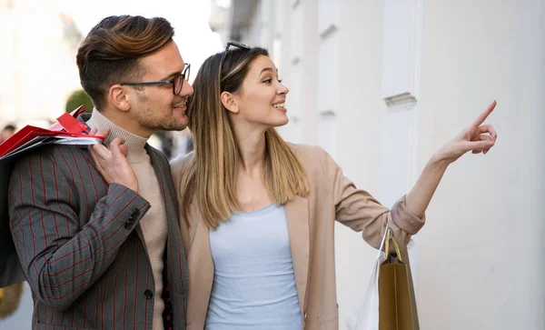 Güzel, genç ve sevgi dolu bir çift alışveriş torbaları taşıyor ve birlikte eğleniyorlar. İnsanlar alışveriş konsepti