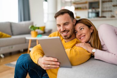 Evde birbirine aşık genç bir çift tablet kullanarak eğleniyor.