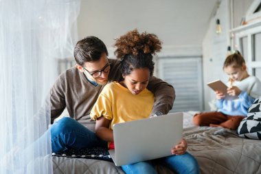 Mutlu bir aile. Baba ve çok ırklı çocuklar evdeki tablette oynuyorlar. Teknoloji, insanlar konsepti