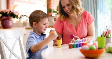 Anne ve oğlu Paskalya yumurta boyama. Mutlu aile Paskalya için hazırlanıyor.