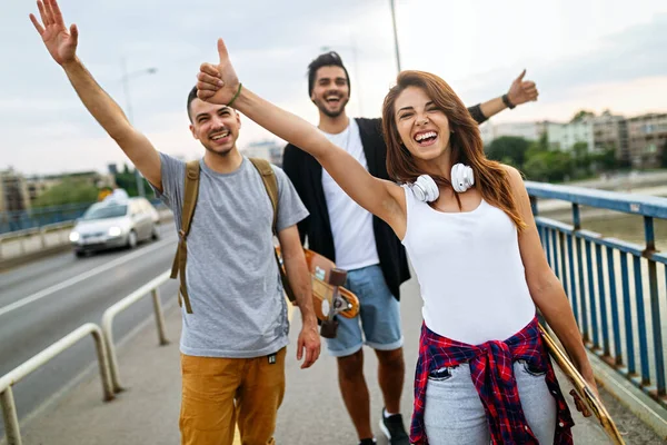 Group of happy friends hang out together and enjoying skateboard outdoors.