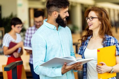 Eğitim kampüsü arkadaşlığı ve insanların konsepti. Bir grup mutlu öğrenci kütüphanede birlikte okuyorlar..