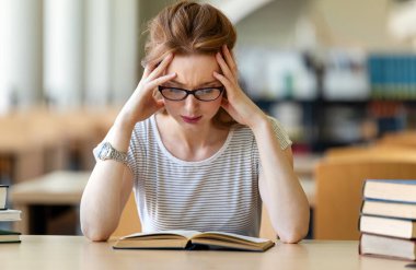 Yorgun genç bir bayan üniversite kütüphanesinde ders çalışıyor ve sınava hazırlanıyor. Eğitim insanları kavramı