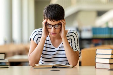 Yorgun genç bir bayan üniversite kütüphanesinde ders çalışıyor ve sınava hazırlanıyor. Eğitim insanları kavramı