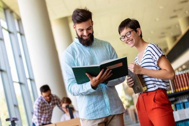 Öğrenciler kütüphanede okuyor. Gençler birlikte zaman geçirip birlikte öğreniyor..