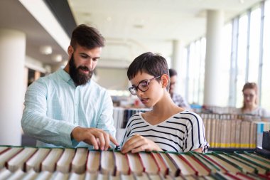 Bir üniversite kütüphanesinde birlikte çalışan mutlu bir öğrenci grubu. Eğitim insanları takım çalışması kavramı.