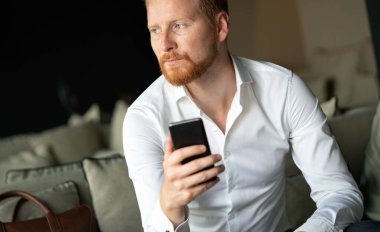 Akıllı telefonunu kullanan mutlu genç bir adam.