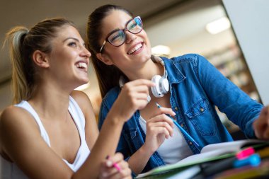 Bir grup mutlu genç arkadaş üniversite kütüphanesinde birlikte okuyorlar. Eğitim insanları kavramını öğren