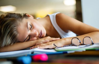 Kütüphanede ders çalışan yorgun genç bir kadının portresi. Eğitim eğitimi gençlik konsepti