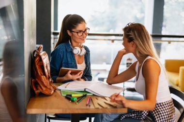 Kütüphanede birlikte ders çalışan mutlu genç arkadaşların portresi. Eğitim eğitimi gençlik konsepti