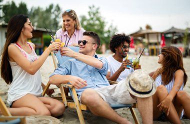Bir grup genç arkadaş güneşli bir günde sahilde eğleniyorlar. İnsanlar tatil mutluluğu içki konsepti.