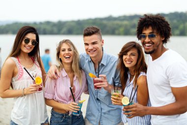 Bir grup genç arkadaş güneşli bir günde sahilde eğleniyorlar. İnsanlar tatil mutluluğu içki konsepti.