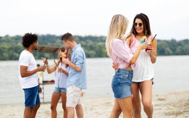 Bir grup genç arkadaş güneşli bir günde sahilde eğleniyorlar. İnsanlar tatil mutluluğu içki konsepti.