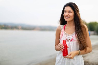Yazın kokteyl içen ve tatilin tadını çıkaran mutlu genç bir kadının portresi.