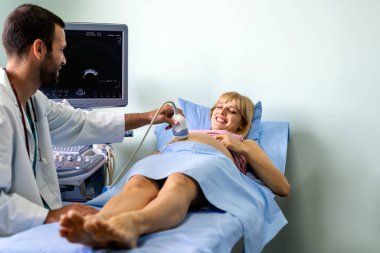 Doğum uzmanı hastanede ultrasonik taramayla hamile kadının karnını muayene ediyor. Sağlık, jinekolog, annelik konsepti..