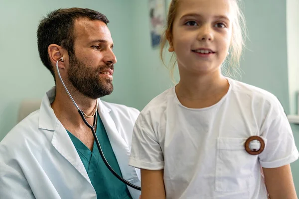 年轻医生在医院用听诊器检查小女孩 儿科概念 — 图库照片
