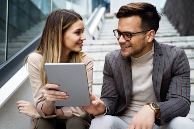 Başarılı genç iş adamları, tasarımcılar konuşuyor, modern iş binası önünde birlikte çalışıyorlar.