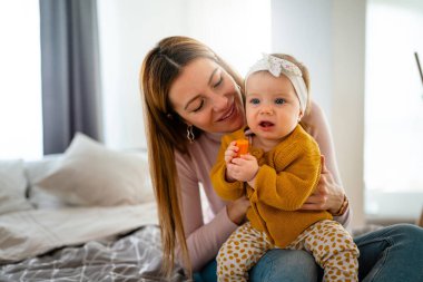 Mutlu bir aile. Anne kız oynuyor, sarılıyor, evde öpüşüyorlar.