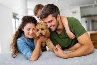 Mutlu genç aile eğleniyor, evde köpeklerle oynuyorlar.