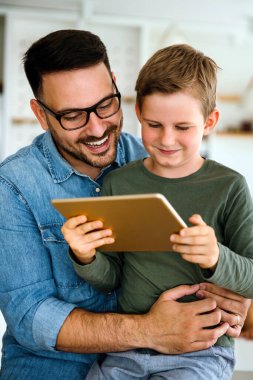 E- öğrenim için dijital tablet kullanan baba ve çocuğun portresi. Eğitimde evde eğitim veren dijital cihaz çocuk kavramı.