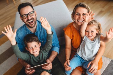 Dijital cihaz teknolojisi aile çevrimiçi eğitim kavramı. Evde dijital cihazları olan mutlu genç bir aile..