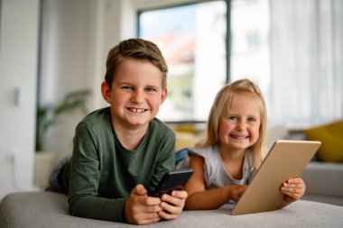 Küçük kız ve oğlan video izliyor ya da dijital cihaz tabletlerinde oyun oynuyorlar, akıllı telefon. Çocuklar dijital bağımlılık kavramı.