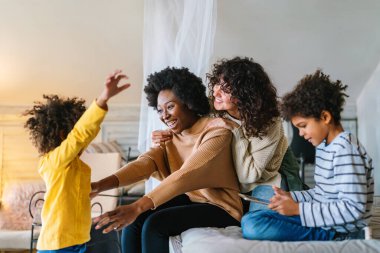 Mutlu çok ırklı aile evde birlikte vakit geçiriyor. Eşcinsel çift çocukları mutluluk kavramını sever