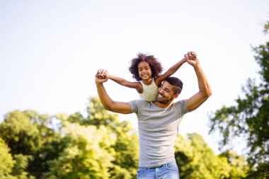 Mutlu Afro-Amerikan baba portresi. Kızı arka bahçede taşıyor. Aile mutluluğu aşk kavramı.