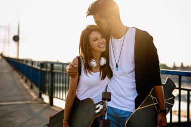 Kaykaylı ve uzun kaykaylı genç bir çiftin açık havada eğlenirken portresi.