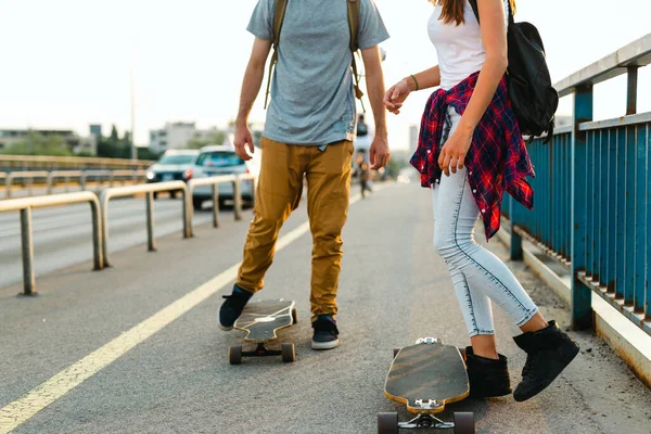 Portrait of happy couple riding skateboards and having fun outdoors. People teenager happiness concept