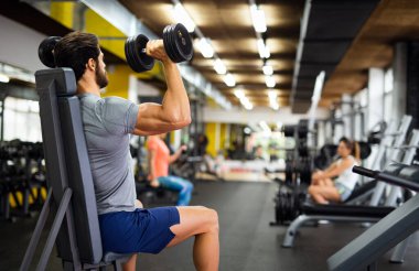 Genç kaslı vücut geliştirici yakışıklı adam spor salonunda egzersiz yapıyor. Spor insanları spor konsepti