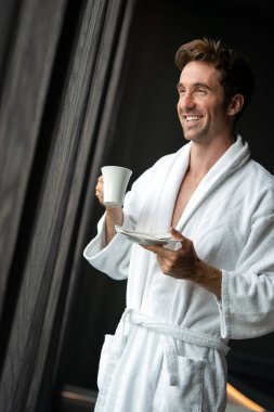 Yakışıklı, kaslı, genç adam sabah kahvesini evde içiyor.