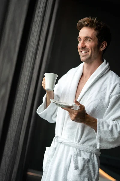 Yakışıklı, kaslı, genç adam sabah kahvesini evde içiyor.