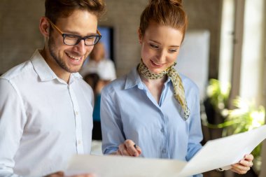 Birlikte yeni bir proje üzerinde çalışıyoruz. Bir grup mutlu iş adamı ofiste bir takım olarak iş birliği yapıyor.