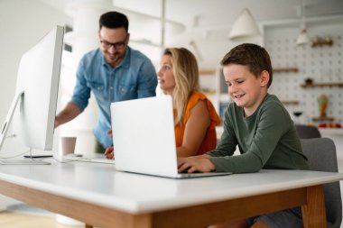 Uzaktan öğrenme, online eğitim, ev işi okulu konsepti. Evde dijital cihazları olan mutlu bir aile.