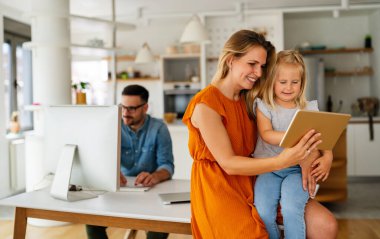 Mutlu aile evde vakit geçiriyor ve dijital cihazları birlikte kullanıyorlar. Teknoloji insanları eğlenceli konsept.