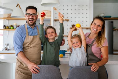 Genç ve mutlu bir aile mutfakta birlikte sağlıklı yemekler hazırlıyor. İnsanlar mutluluk aşçılık konsepti