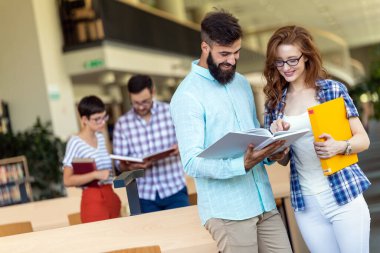 Öğrenciler kütüphanede okuyor. Gençler birlikte zaman geçirip birlikte öğreniyor..