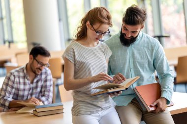 Bir üniversite kütüphanesinde birlikte çalışan mutlu bir öğrenci grubu. Eğitim insanları takım çalışması kavramı.