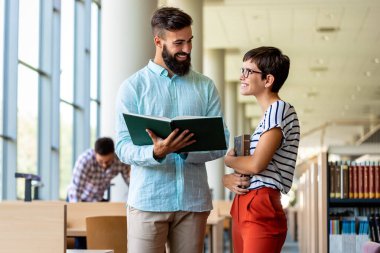 Bir üniversite kütüphanesinde birlikte çalışan mutlu bir öğrenci grubu. Eğitim insanları takım çalışması kavramı.