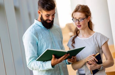 Kütüphanede kitaplarla çalışan mutlu genç üniversite öğrencileri. Üniversitede bir grup çok ırklı insan