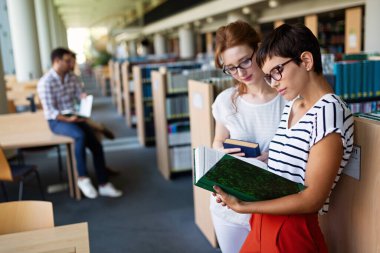 Öğrenciler kütüphanede okuyor. Gençler birlikte zaman geçirip birlikte öğreniyor..