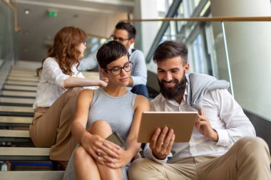 Modern ofisteki iş arkadaşları birlikte çalışıp tablet kullanıyorlar.