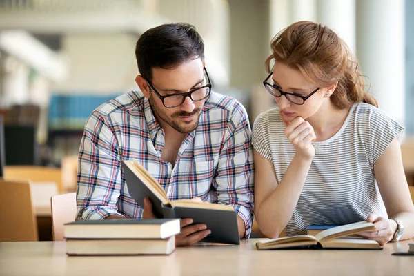 Bir üniversite kütüphanesinde birlikte çalışan mutlu bir öğrenci grubu. Eğitim insanları takım çalışması kavramı.
