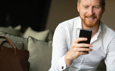 Ofiste cep telefonu kullanan başarılı bir iş adamı. İş, teknoloji, insan kavramı