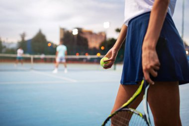 Raketi ve topuyla genç ve yakışıklı bayan tenisçi oyunun başında veya maçın başında servis yapmaya hazırlanıyor.