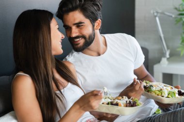 İyi sabahlar. Yatakta sağlıklı bir kahvaltı. Genç ve güzel bir çift birlikte vakit geçiriyorlar.